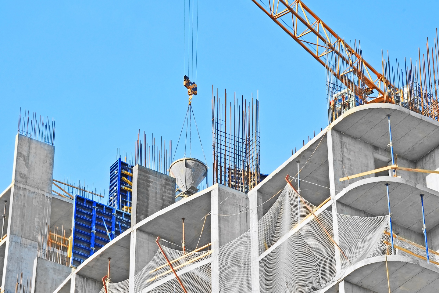 Construction work on a large building against a blue sky